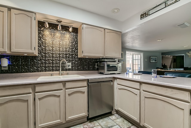 kitchen with backsplash, light countertops, stainless steel dishwasher, stone finish floor, and a sink