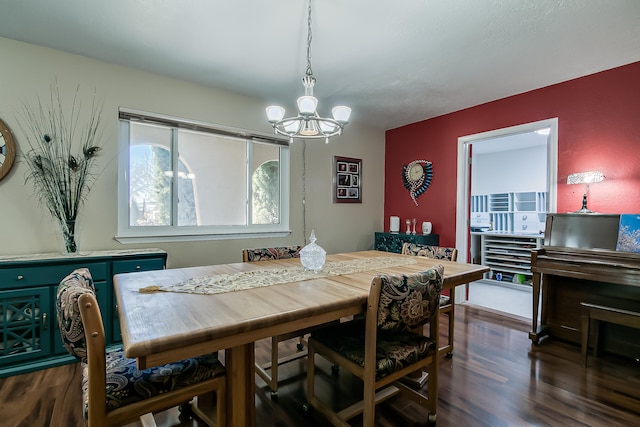 dining space with dark wood-style floors and an inviting chandelier