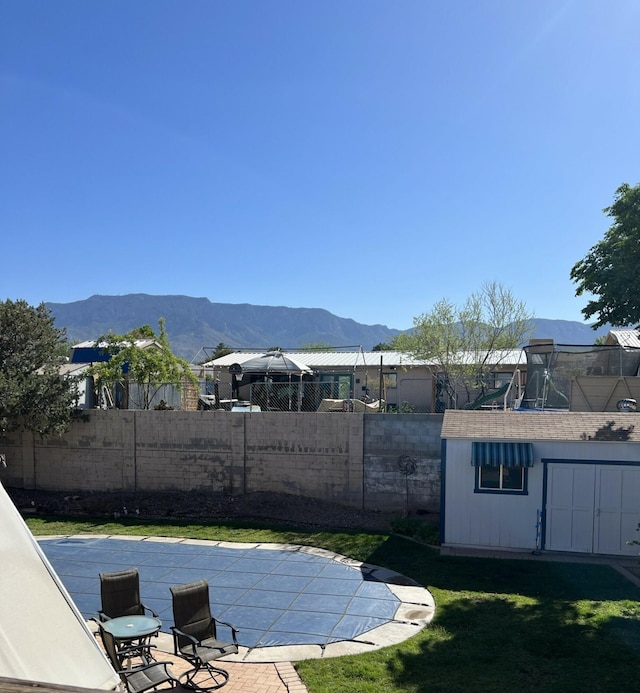 view of swimming pool featuring a fenced in pool, fence, an outdoor structure, a mountain view, and a patio