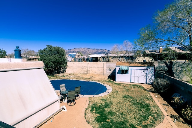 view of pool with an outbuilding, a yard, a fenced backyard, a storage shed, and a mountain view