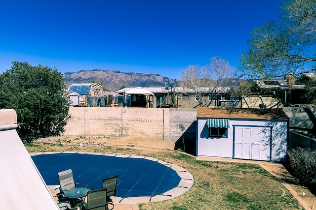 view of yard with a storage shed, an outbuilding, fence private yard, and a mountain view