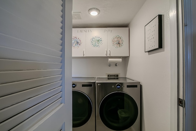 washroom with cabinet space, separate washer and dryer, and visible vents