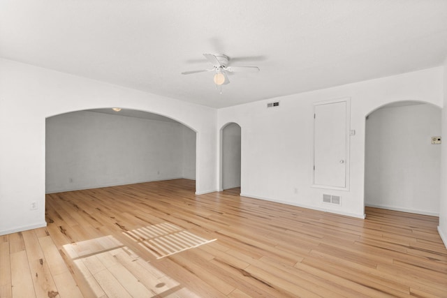 empty room featuring a ceiling fan, visible vents, and arched walkways