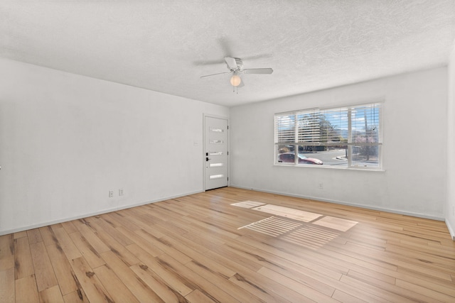 spare room featuring baseboards, a textured ceiling, ceiling fan, and wood finished floors