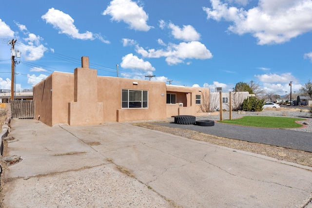 rear view of house featuring stucco siding and fence