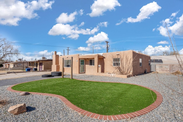 back of house featuring stucco siding, a lawn, and fence