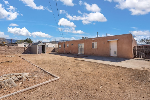 back of house with a patio, an outbuilding, a fenced backyard, stucco siding, and a storage shed