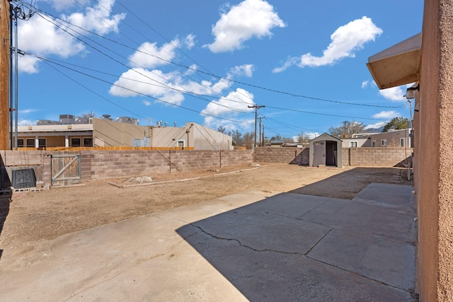 view of yard with a storage unit, a patio, an outdoor structure, and a fenced backyard