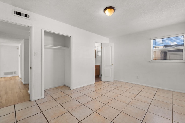 unfurnished bedroom with a closet, visible vents, and a textured ceiling