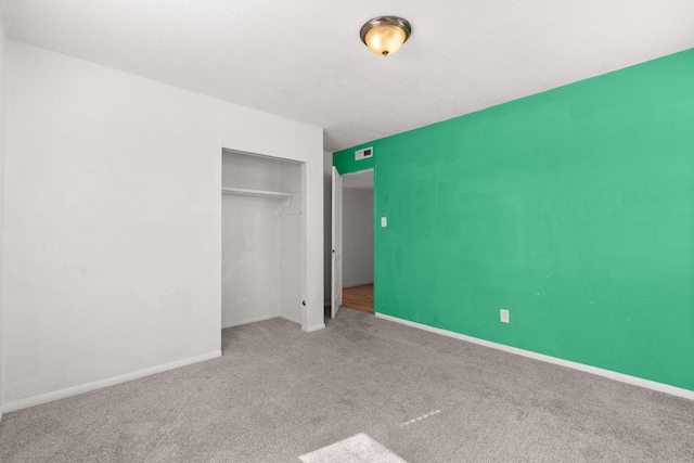 unfurnished bedroom featuring visible vents, baseboards, carpet floors, a closet, and a textured ceiling