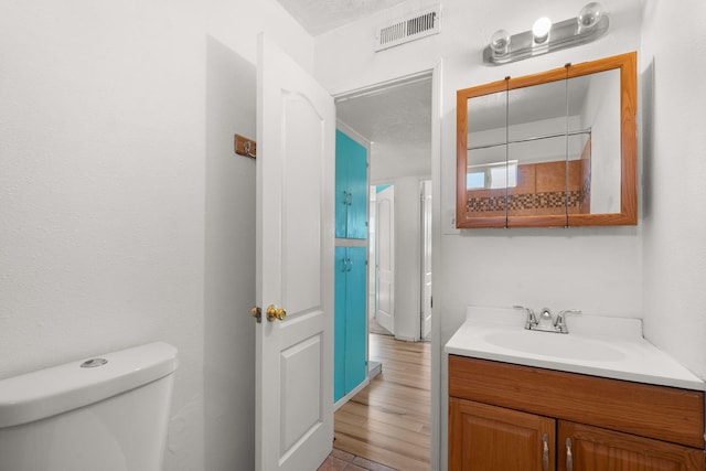 bathroom featuring visible vents, toilet, and vanity