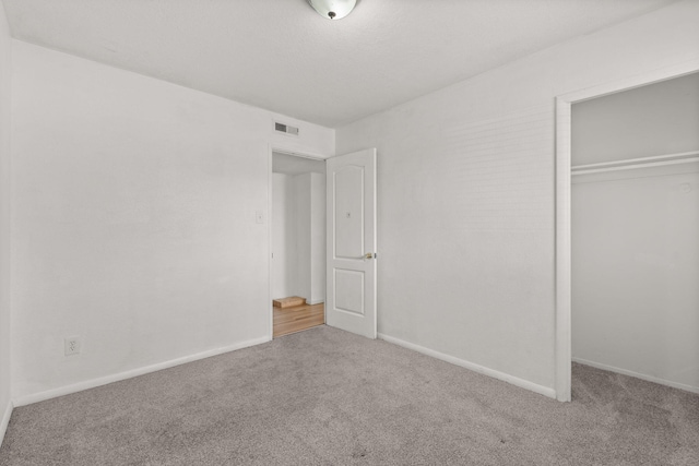 unfurnished bedroom featuring carpet, visible vents, a closet, and baseboards