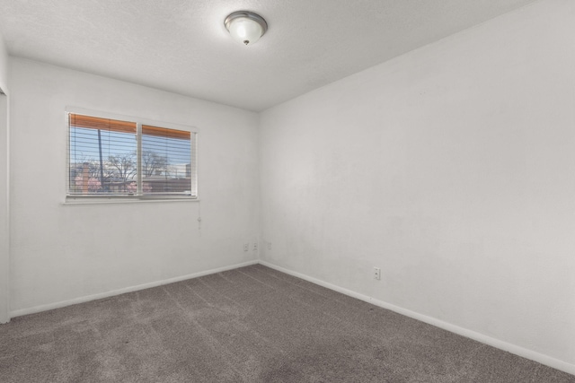 spare room featuring carpet flooring, a textured ceiling, and baseboards