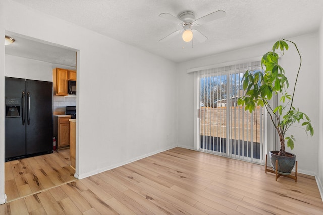 unfurnished room featuring light wood-type flooring, baseboards, a textured ceiling, and a ceiling fan