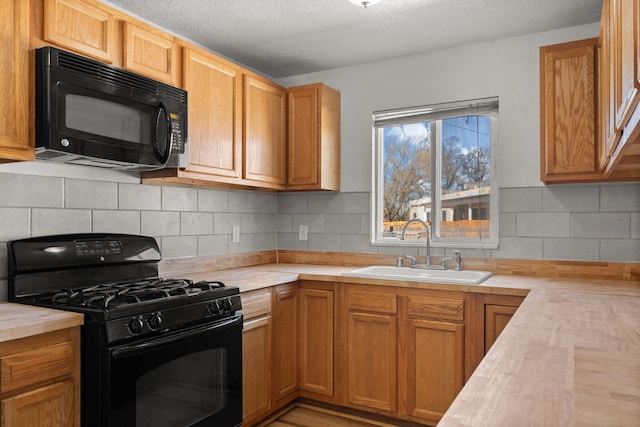 kitchen featuring a sink, backsplash, black appliances, and a textured ceiling