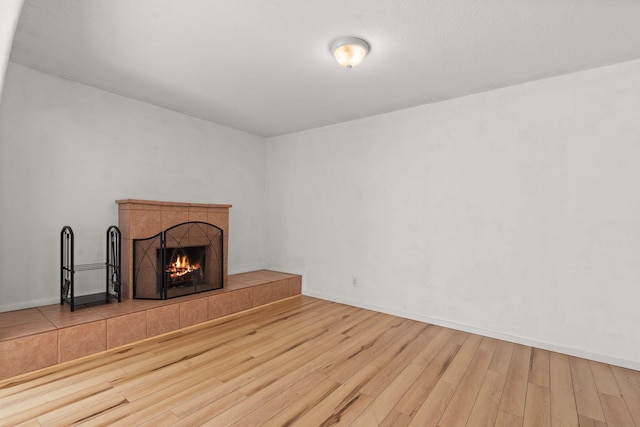 unfurnished living room with baseboards, wood finished floors, and a fireplace