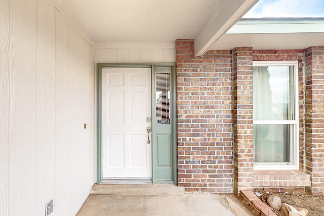 view of exterior entry featuring brick siding