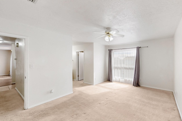 spare room with baseboards, light colored carpet, a textured ceiling, and a ceiling fan