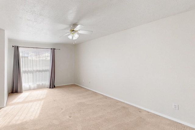 spare room with a textured ceiling, a ceiling fan, baseboards, and light carpet