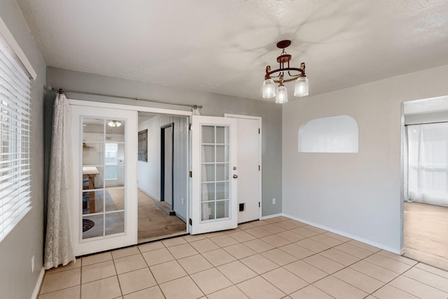 spare room with baseboards, a notable chandelier, and light tile patterned flooring