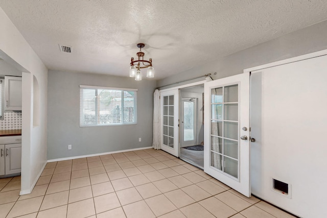 empty room with light tile patterned floors, baseboards, visible vents, french doors, and a chandelier