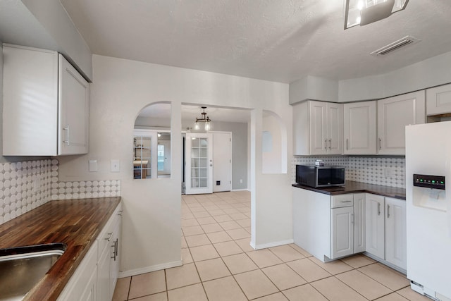 kitchen featuring visible vents, arched walkways, a sink, white fridge with ice dispenser, and stainless steel microwave