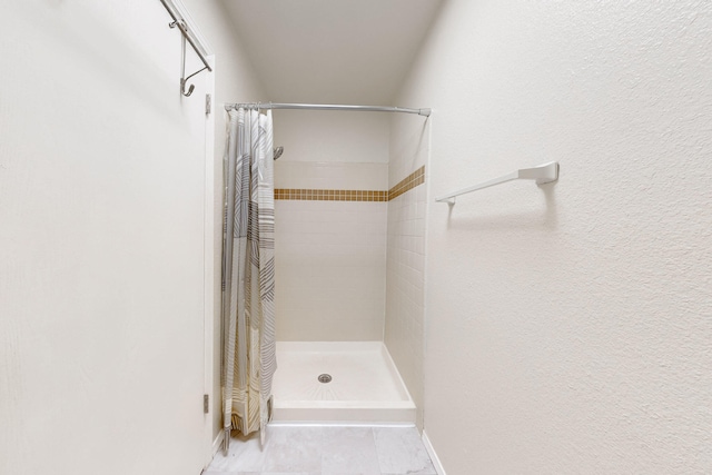 bathroom with baseboards and a stall shower