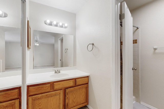 bathroom featuring vanity, a tile shower, and ceiling fan