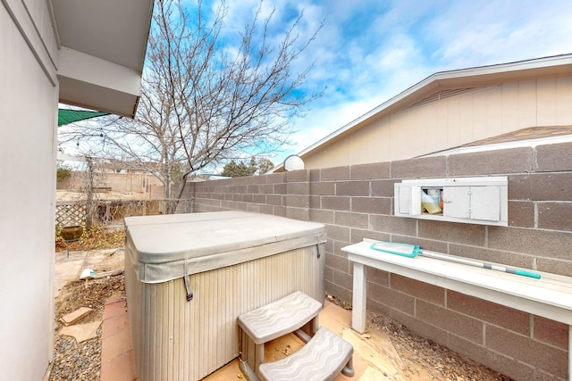 view of patio / terrace featuring fence and a hot tub