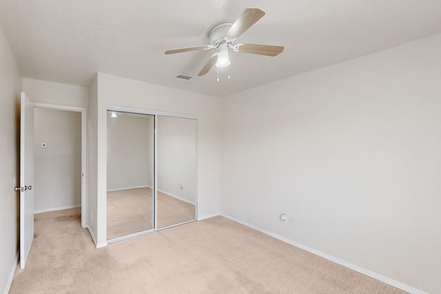 unfurnished bedroom featuring a closet, baseboards, light colored carpet, and visible vents