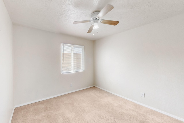 spare room featuring baseboards, light colored carpet, a textured ceiling, and a ceiling fan