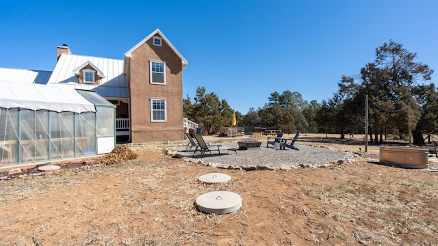 view of yard featuring a greenhouse, a fire pit, and an outbuilding