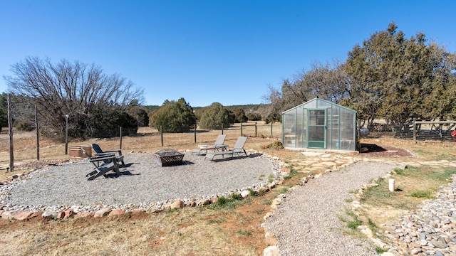 view of yard featuring an exterior structure, an outbuilding, an outdoor fire pit, and fence