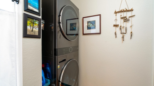 laundry area with laundry area, stacked washer / dryer, and a textured wall