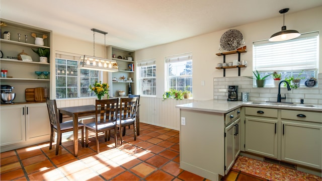 kitchen with open shelves, a peninsula, a sink, light countertops, and decorative light fixtures