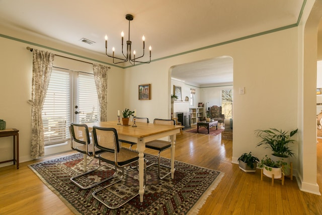 dining room with light wood-style flooring, visible vents, and arched walkways