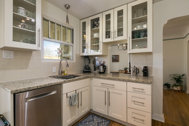 kitchen with a sink, light stone counters, stainless steel dishwasher, and white cabinetry