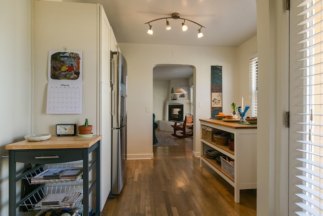 hall with baseboards, arched walkways, and dark wood-style floors