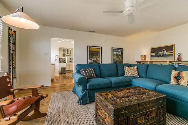 living room featuring arched walkways, wood finished floors, visible vents, and ceiling fan