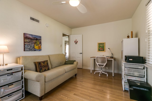 living area featuring light wood-type flooring, visible vents, baseboards, and a ceiling fan