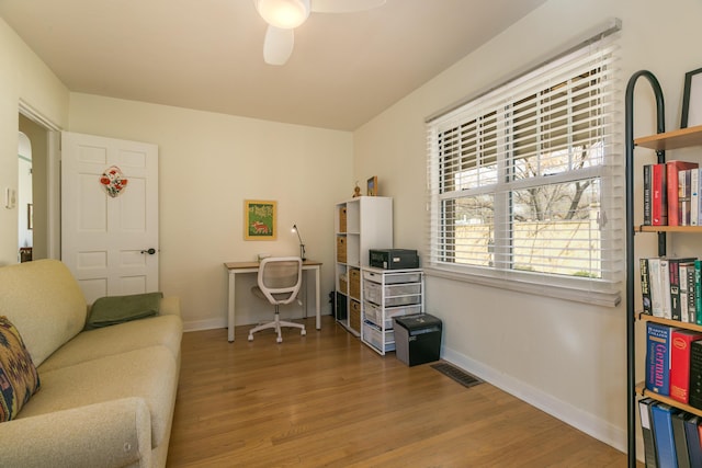 office space featuring wood finished floors, a ceiling fan, visible vents, and baseboards