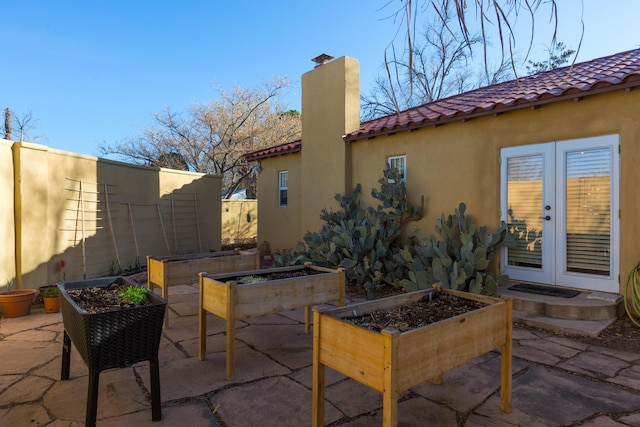 view of patio / terrace with a vegetable garden, french doors, and fence