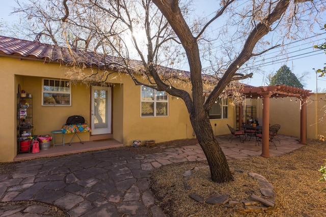 rear view of house with stucco siding, a patio, a tile roof, and a pergola