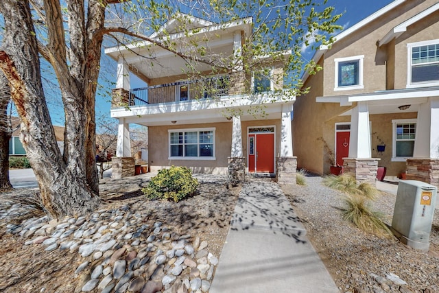 view of front of house featuring a balcony, covered porch, and stucco siding