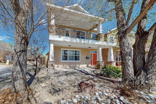 view of front facade featuring a porch, a balcony, and stucco siding