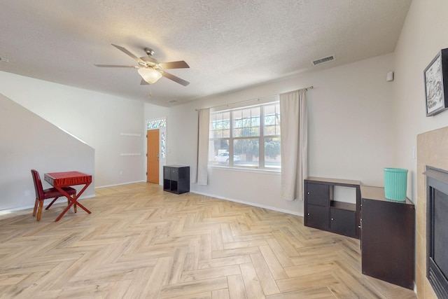 living area featuring visible vents, a textured ceiling, a fireplace, baseboards, and ceiling fan