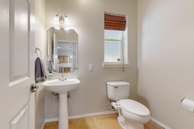 half bathroom with tile patterned floors, baseboards, and toilet