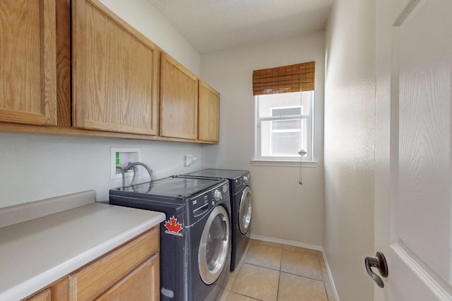 laundry area featuring light tile patterned floors, baseboards, cabinet space, and separate washer and dryer