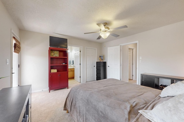 bedroom with a ceiling fan, baseboards, ensuite bathroom, a textured ceiling, and light colored carpet