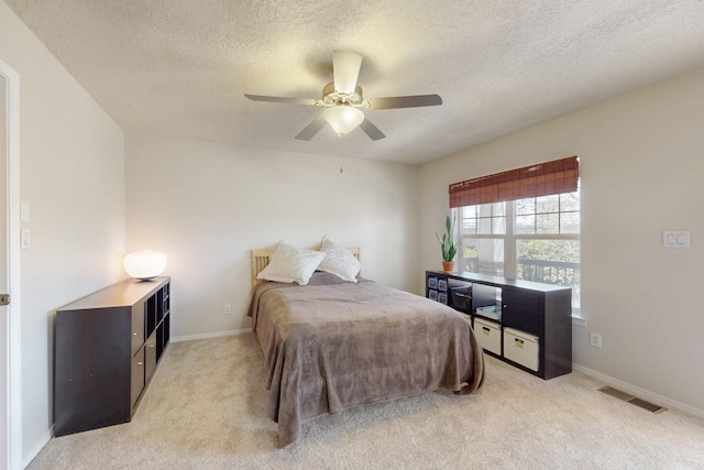 bedroom featuring a textured ceiling, light colored carpet, visible vents, and baseboards